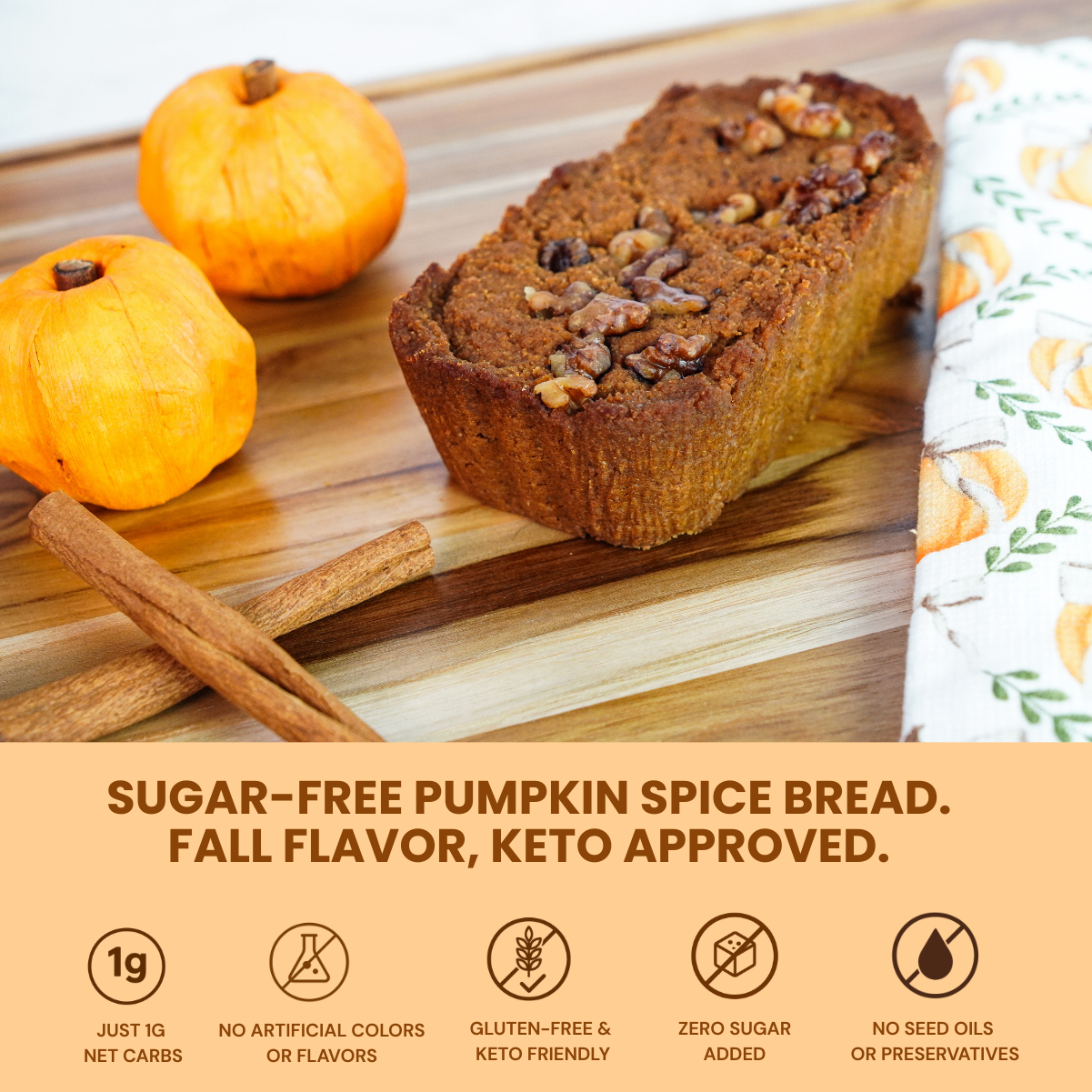 Keto Pumpkin Spice Bread displayed on wooden board with cinnamon sticks, mini pumpkins, and a festive pumpkin-print napkin. Icons highlight low carb and clean ingredient benefits.