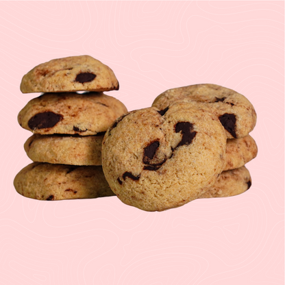 A stack of golden-brown, sugar-free chocolate chip cookies with rich, melty chocolate chunks, set against a soft pink background. Perfectly baked for a classic, guilt-free indulgence.